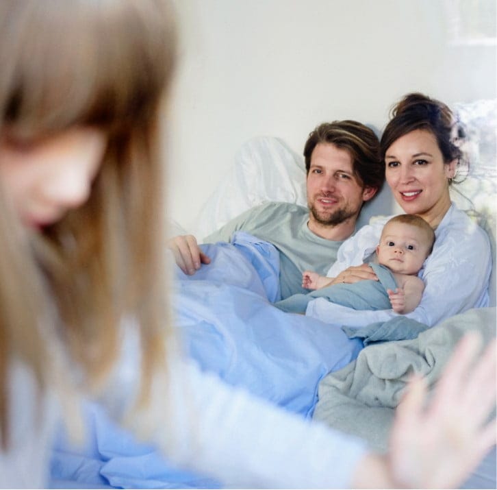 Eltern mit Neugeborenem im Bett