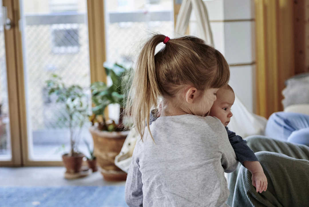 Kleinkind mit Baby im Arm